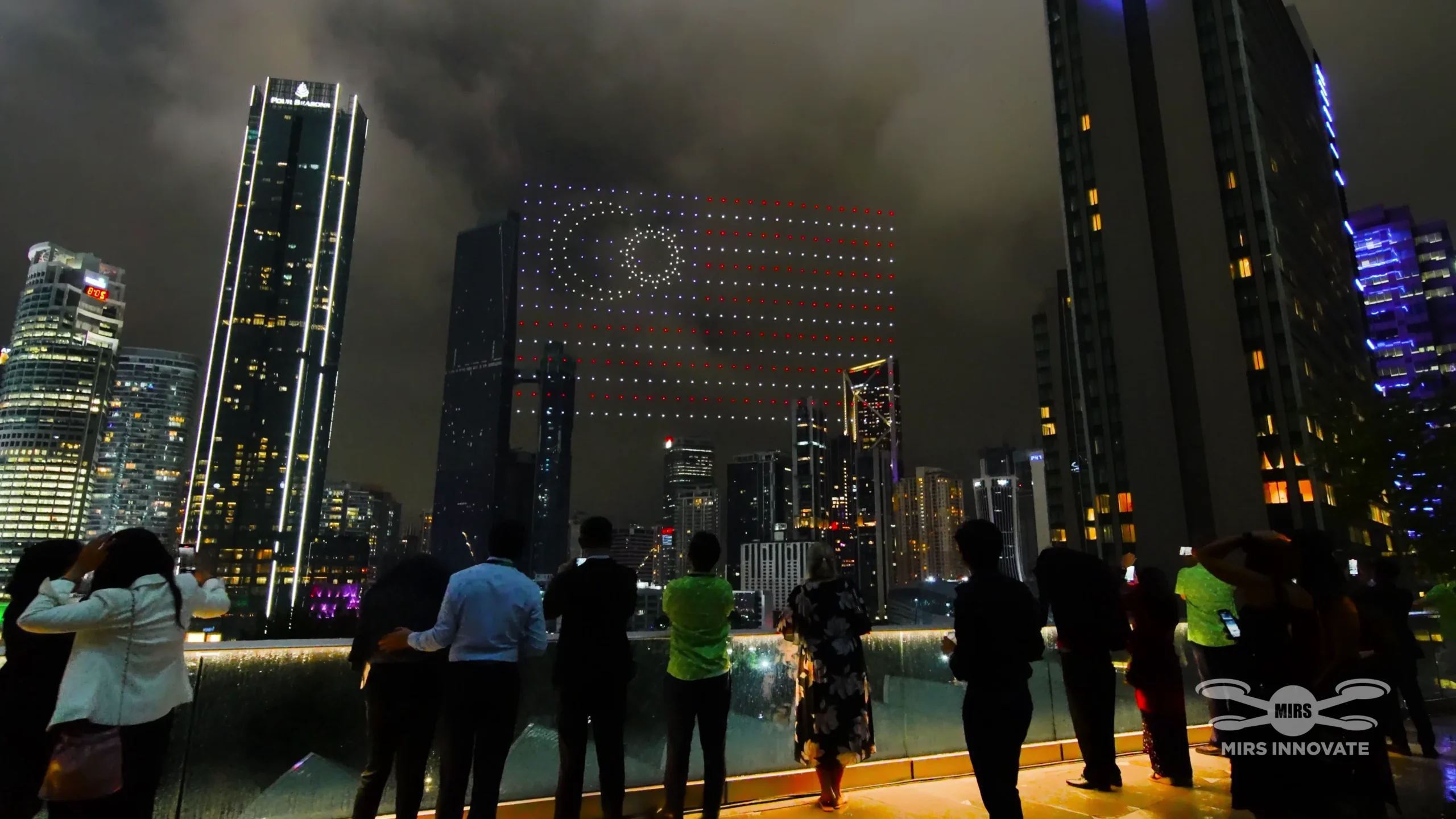 Drone formation against KLCC building facade with crowd watching Deloitte 25th anniversary show