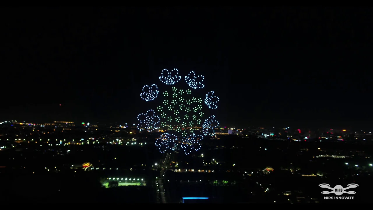 White and green floral drone formation above city lights