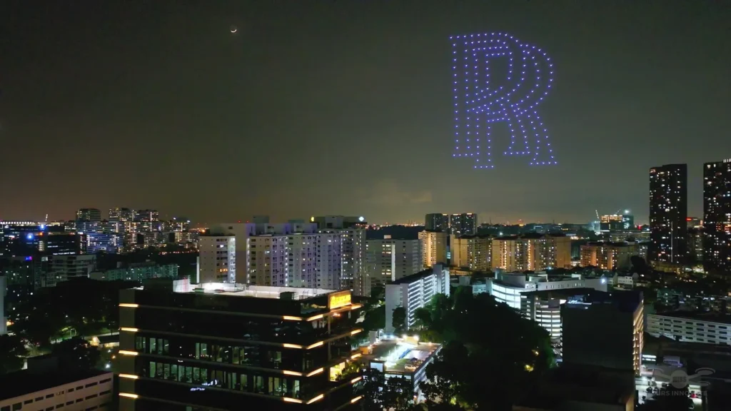 Illuminated letter R drone formation above a city skyline during a brand event in Singapore