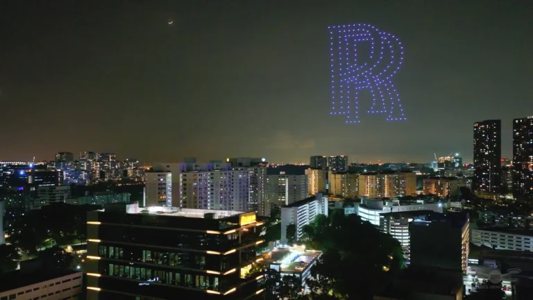 Illuminated letter R drone formation above a city skyline during a brand event in Singapore
