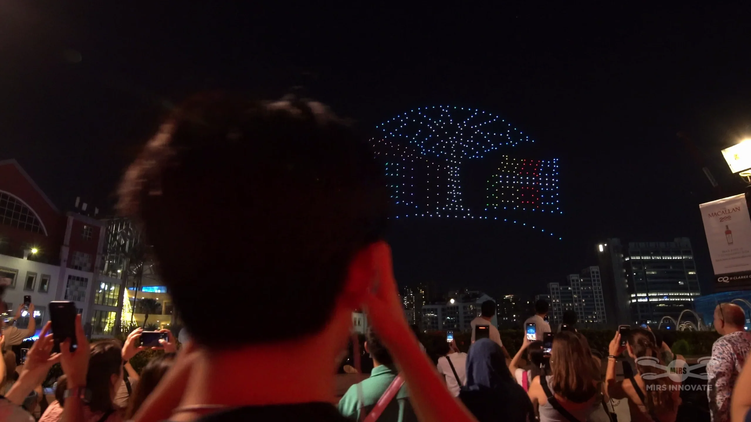 Audience recording a drone formation during the F1 CQ drone show in Singapore