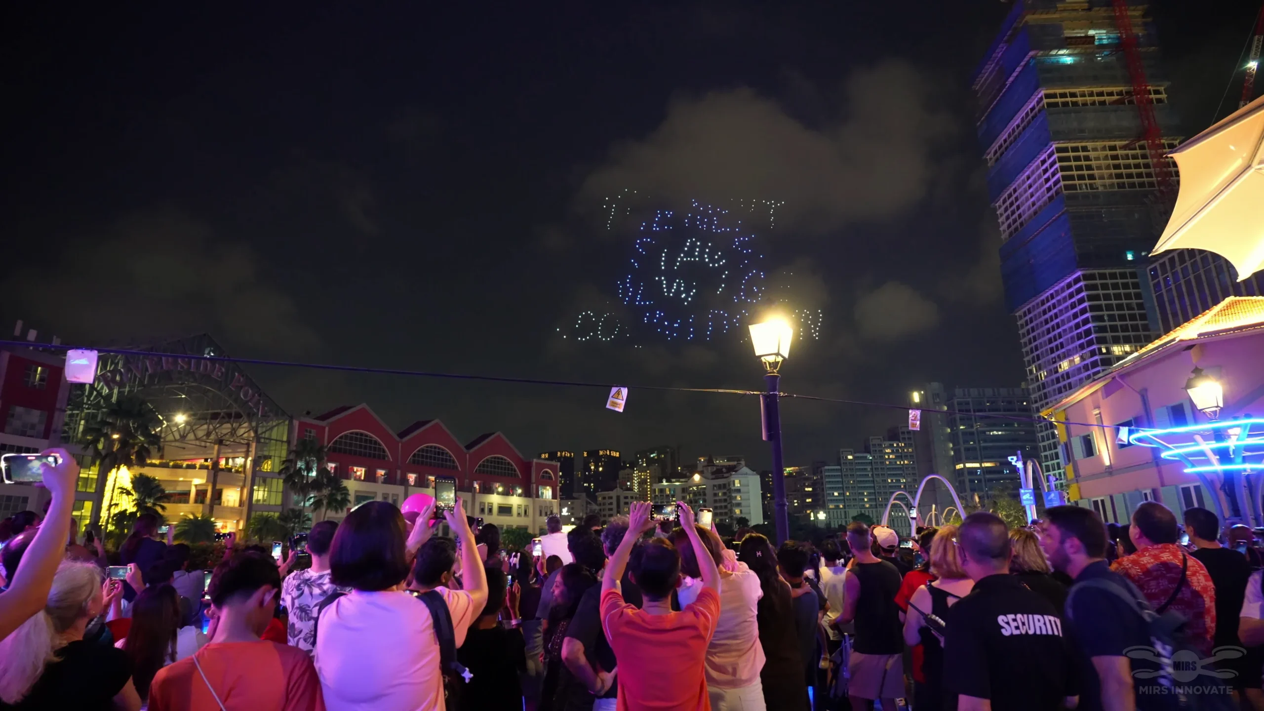Crowd watching countdown text drone formation above Clarke Quay Singapore