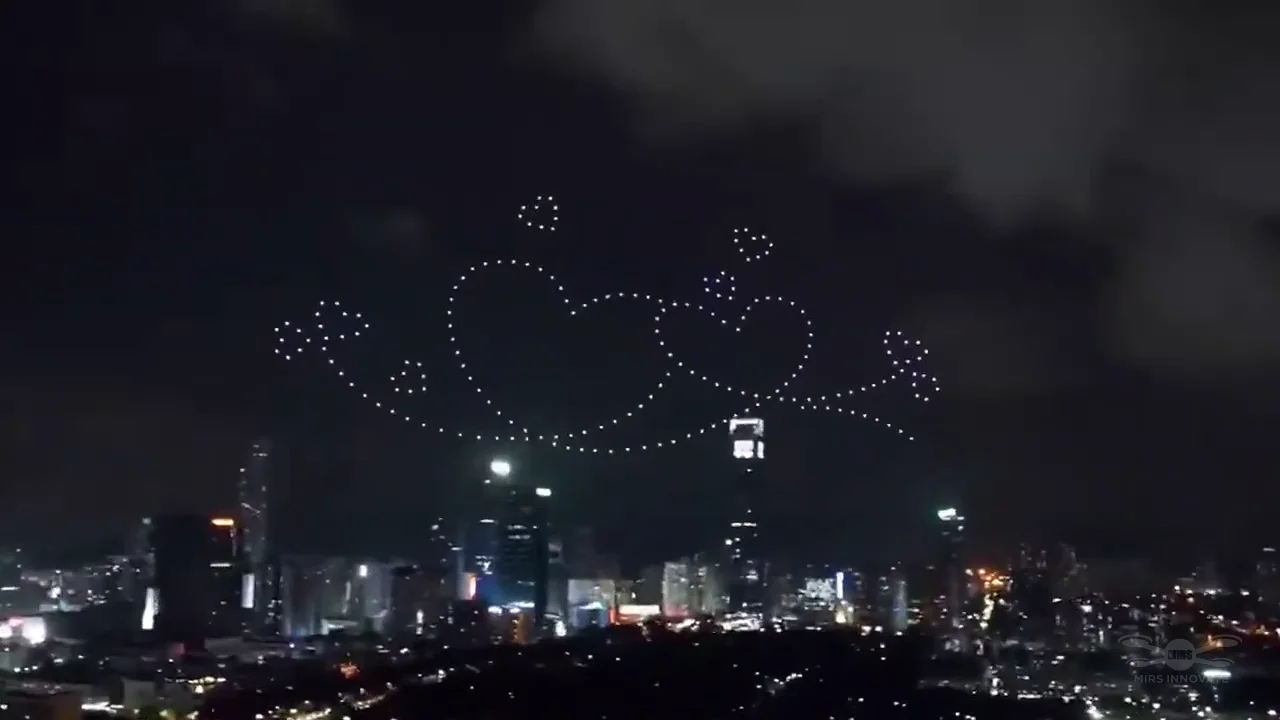 Interlocking hearts and sparkles formed by 200 drones above an overseas cityscape